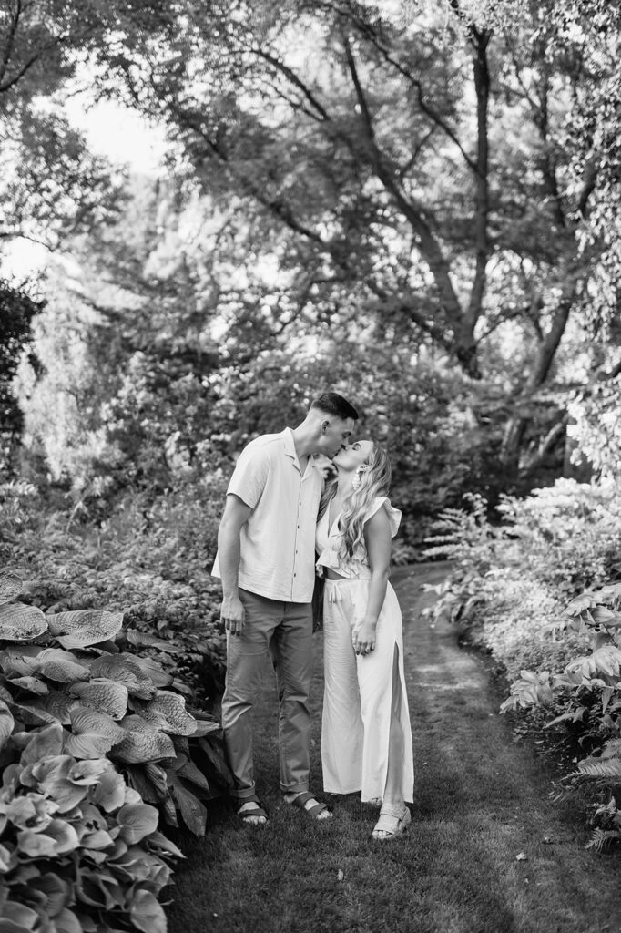 Black and white engagement photo of a couple kissing at Hamstra Gardens in Wheatfield, Indiana for their engagement session