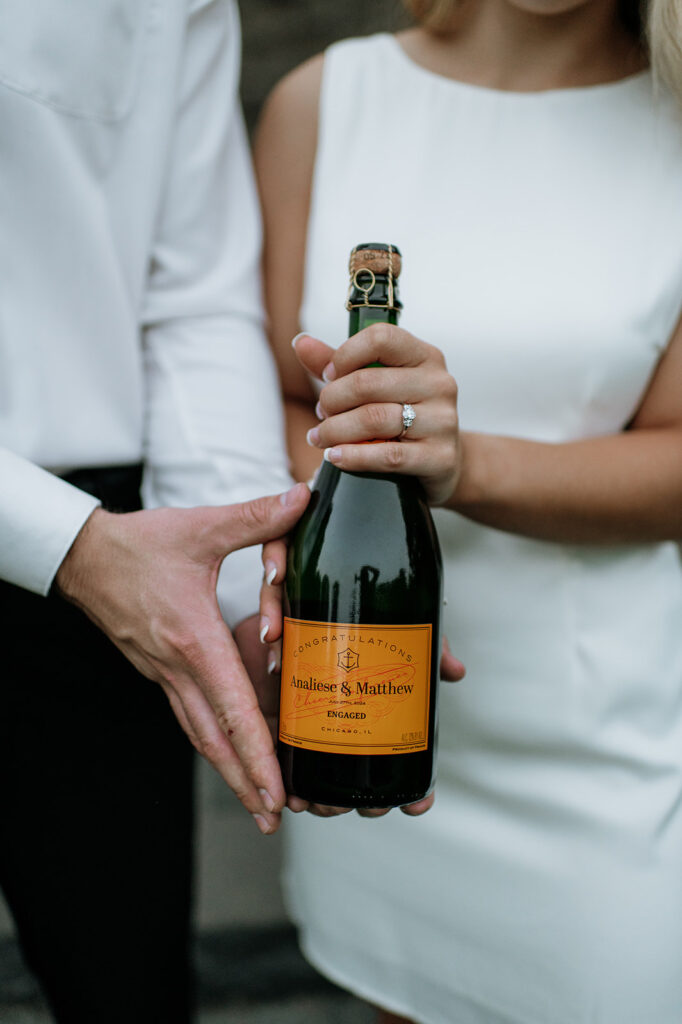 Couple holding a bottle of champagne with a custom label for their engagement