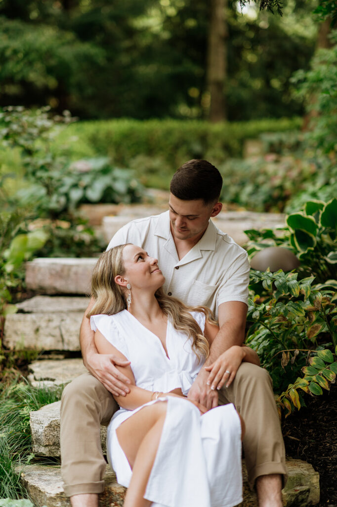 Couple sitting on steps and posing for their engagement shoot