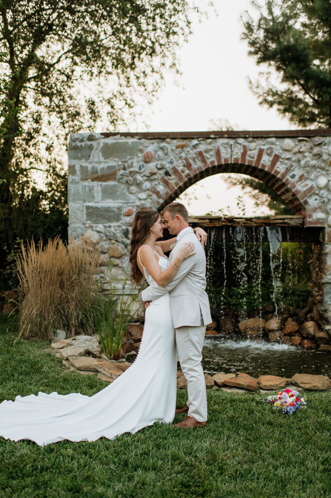 Bride and groom kissing in front of a rustic stone waterfall