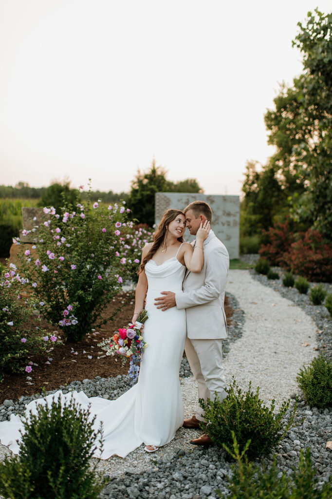 Bride and groom posing in the gardens at Empeiria 110 wedding venue