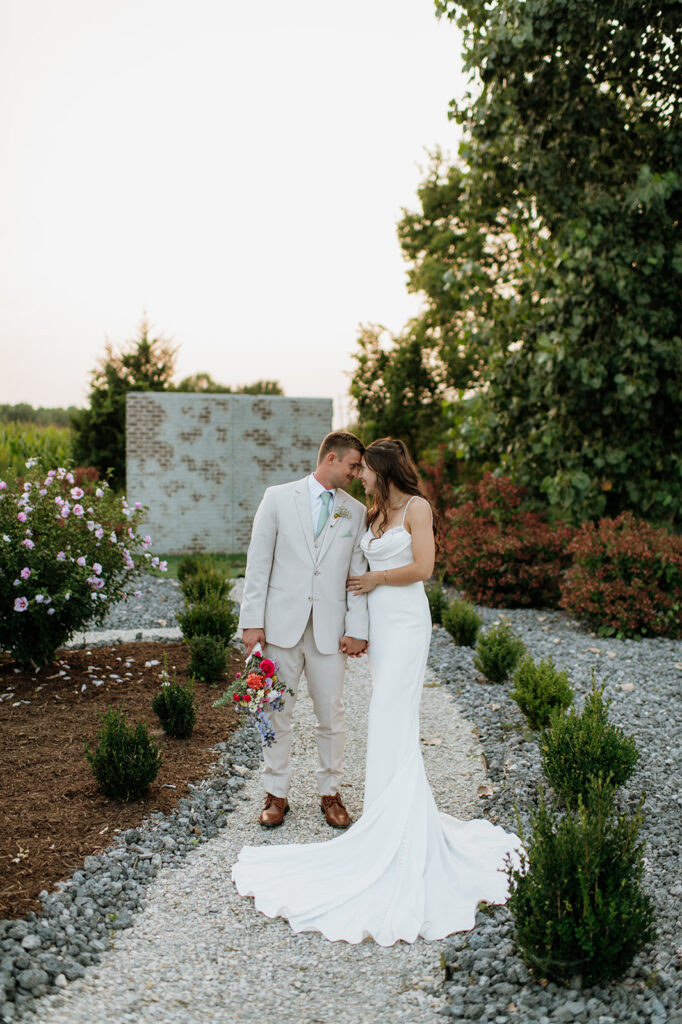 Bride and groom posing in the gardens at Empeiria 110 wedding venue