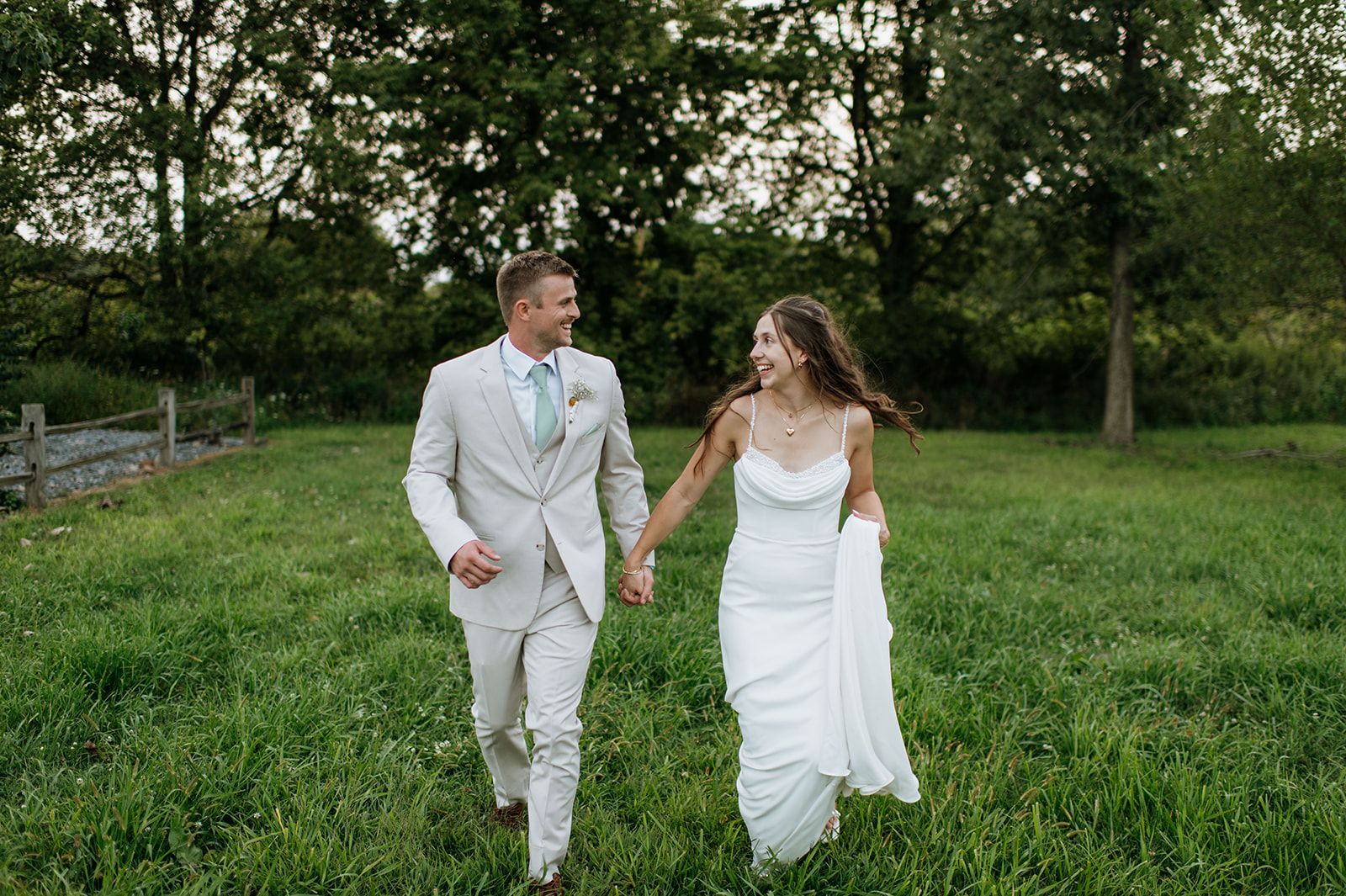 Bride and groom running in an open field