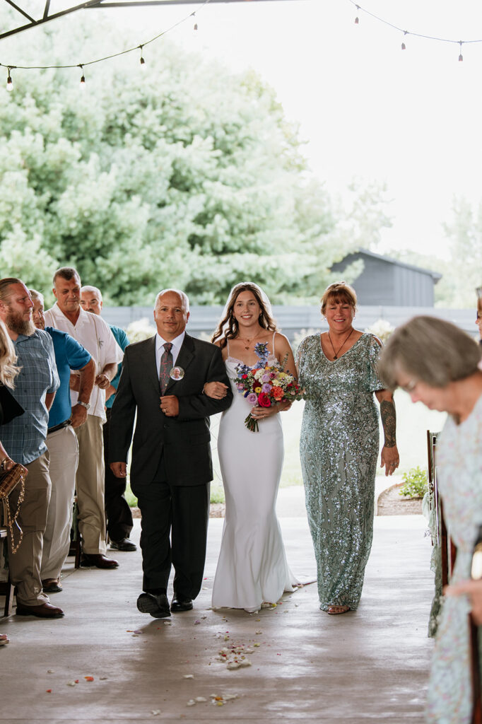 Bride being walked down the aisle by family