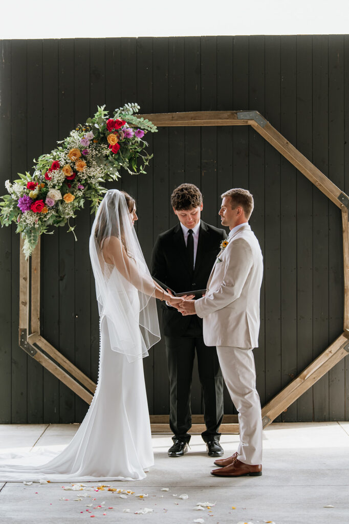 Bride and groom holding hands during their Empeiria 110 wedding ceremony underneath the pavilion 