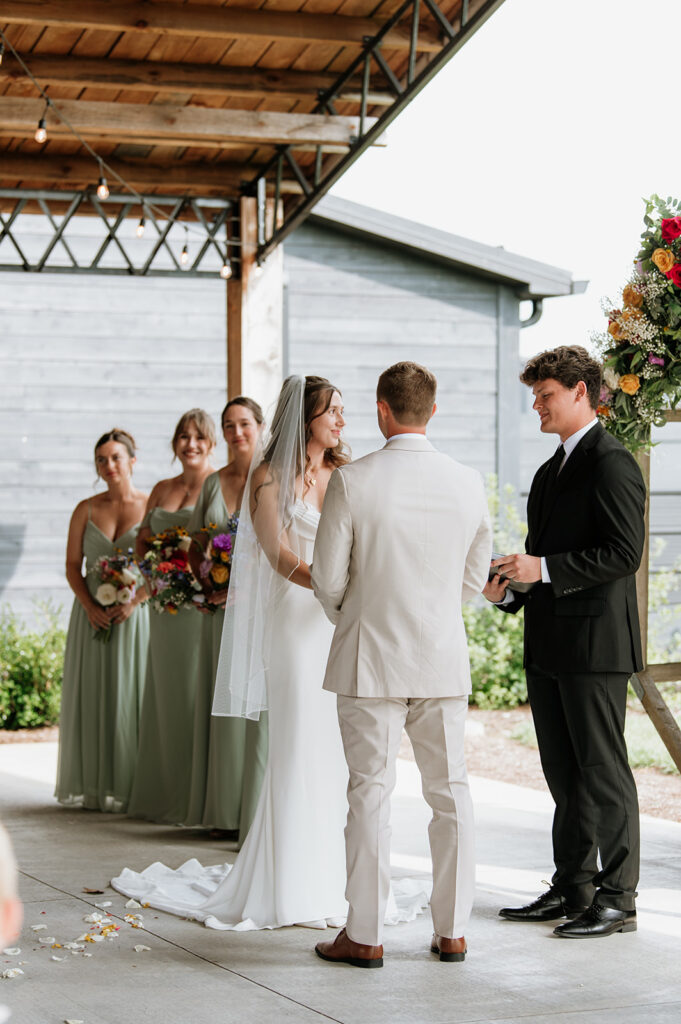 Bride and groom holding hands during their outdoor Empeiria 110 wedding ceremony underneath the pavilion 