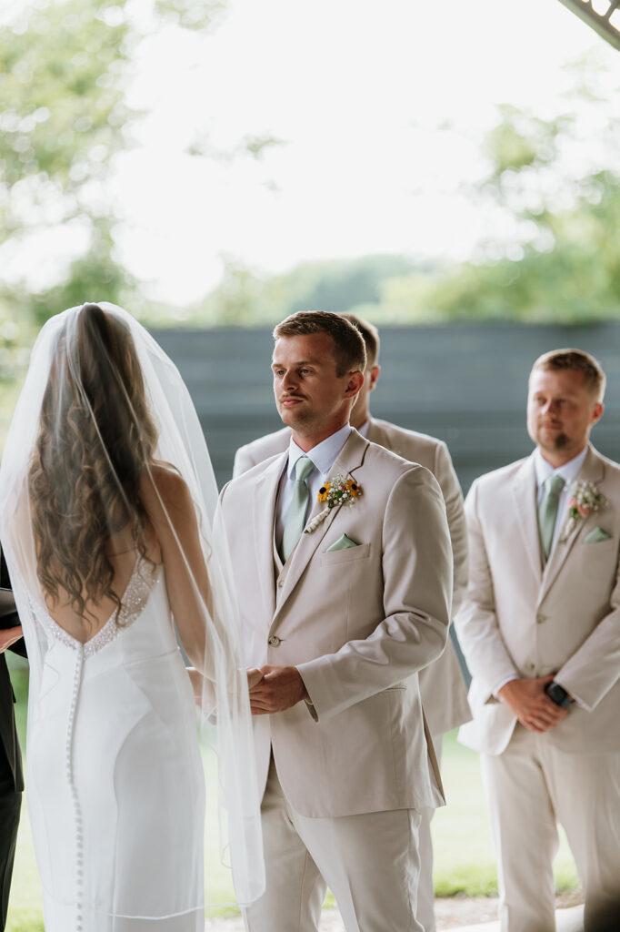 Bride and groom holding hands during their outdoor Empeiria 110 wedding ceremony underneath the pavilion 