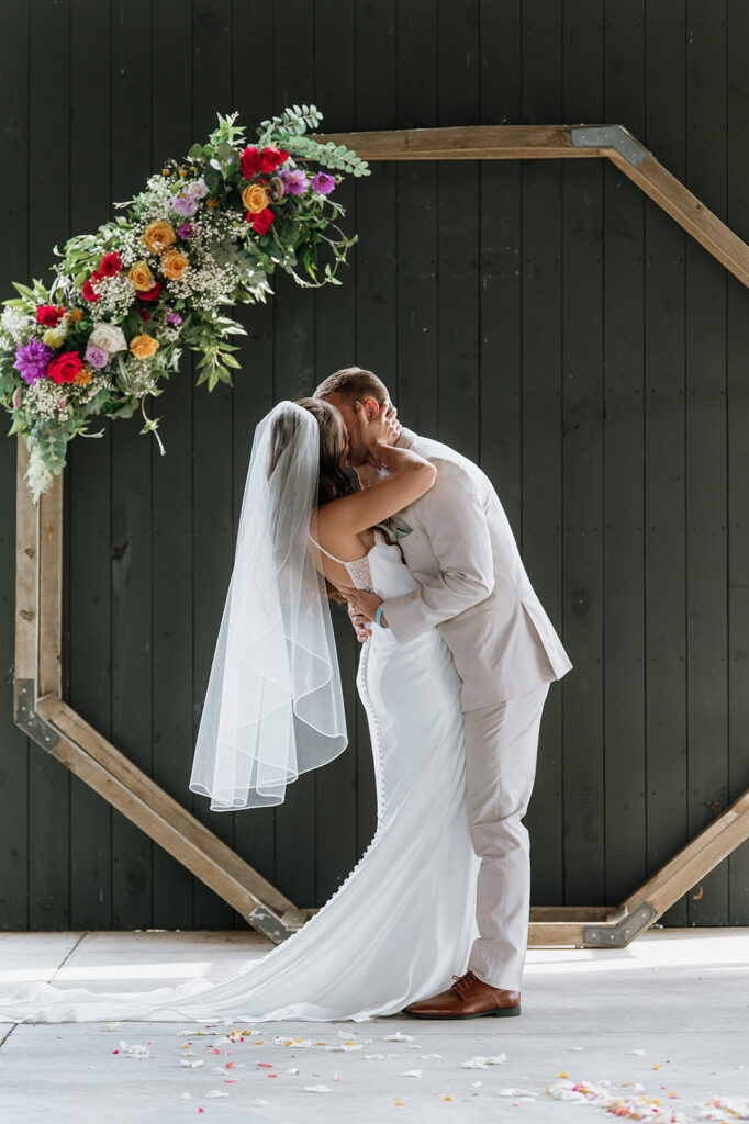 Bride and groom kissing during their outdoor Empeiria 110 wedding ceremony underneath the pavilion 