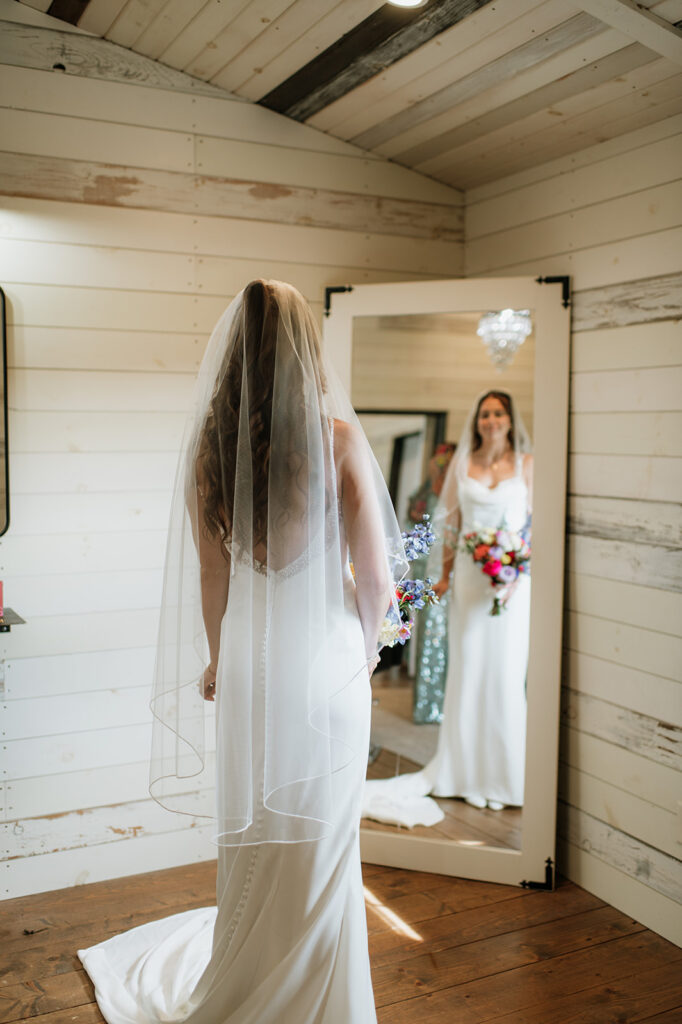 Bride looking at herself in the mirror in her full wedding attire