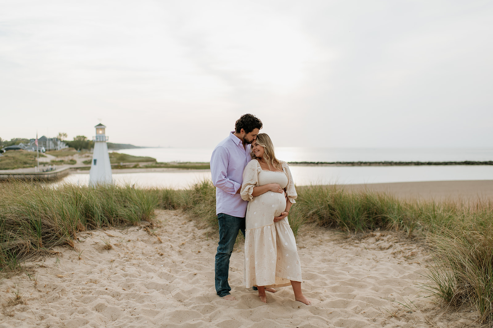 Man and woman posing at New Buffalo Beach for their Michigan maternity photos