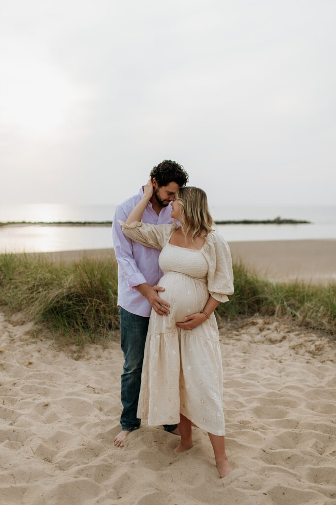 Man and woman posing for their New Buffalo Beach maternity photos in Michigan