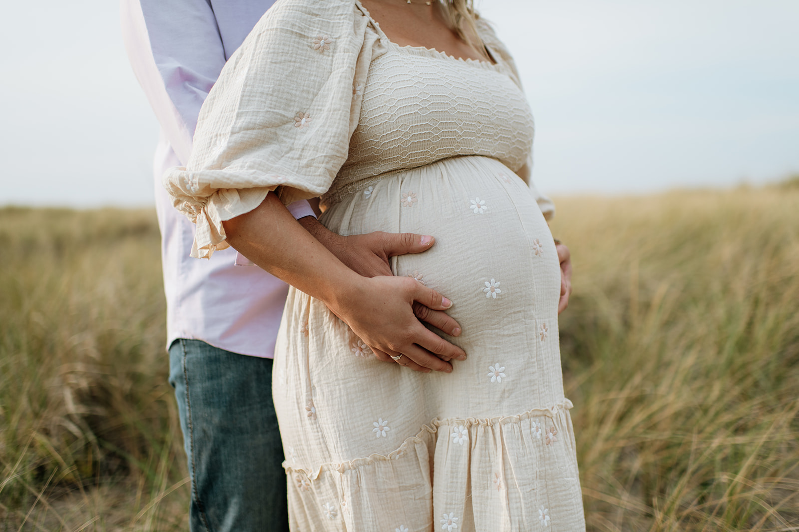 Man and woman holding her pregnant belly during their maternity photos in Michigan