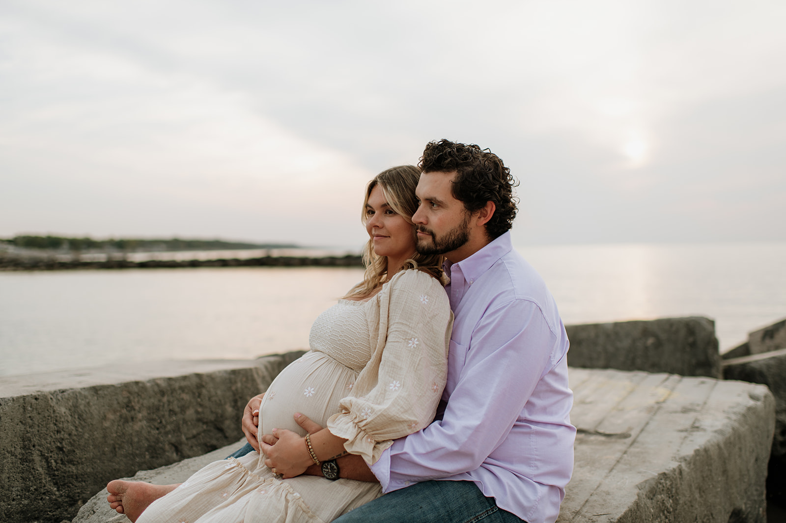 Couple sitting together at New Buffalo Beach for their Michigan maternity photos