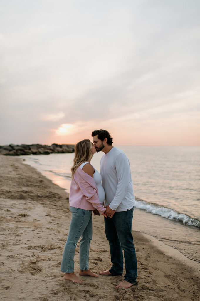 Couple kissing on New Buffalo Beach during their dreamy sunset Michigan maternity photos