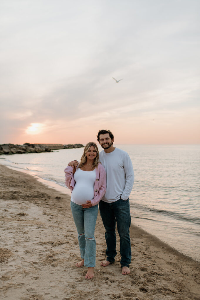 Couple posing on New Buffalo Beach for their sunset maternity photos in Michigan