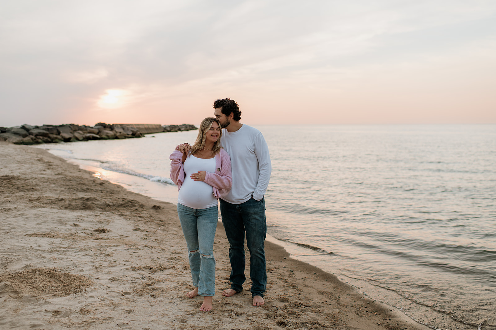 Man kissing his wifes head during their maternity photos in Michigan