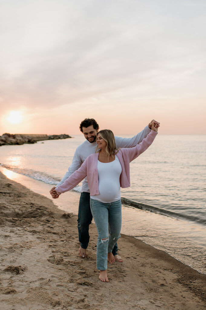 Couple doing playful poses during their beach maternity session