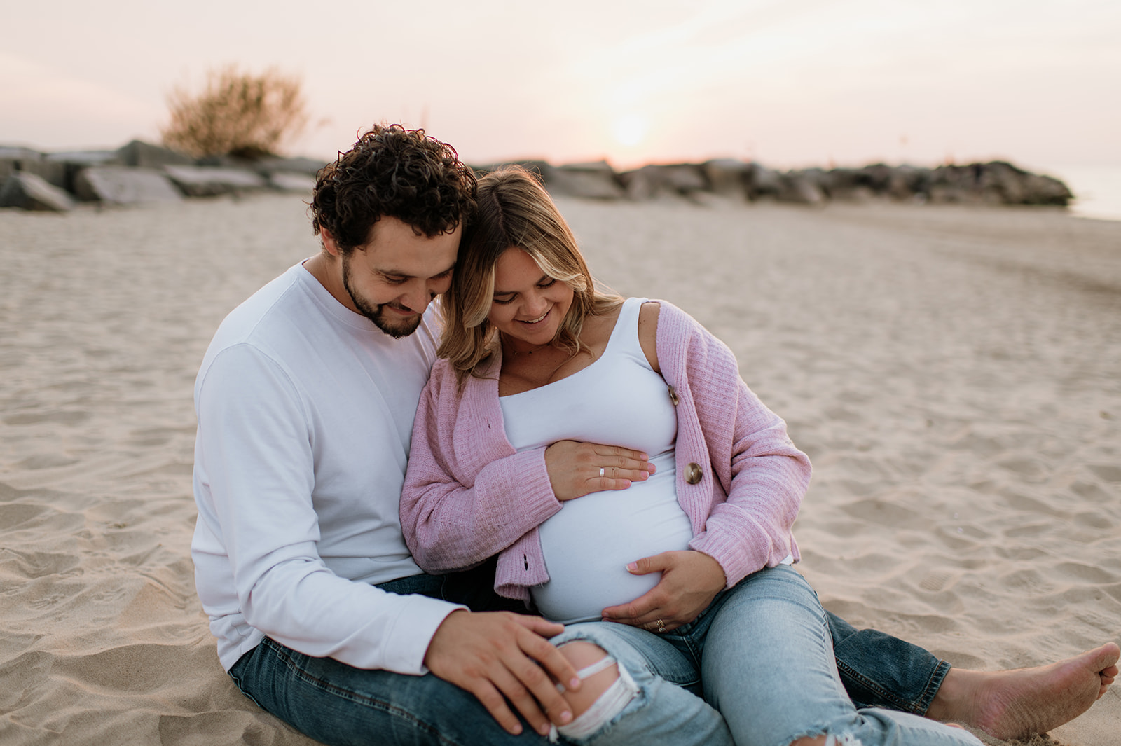 Couple admiring the woman's pregnant belly during their Michigan maternity photos