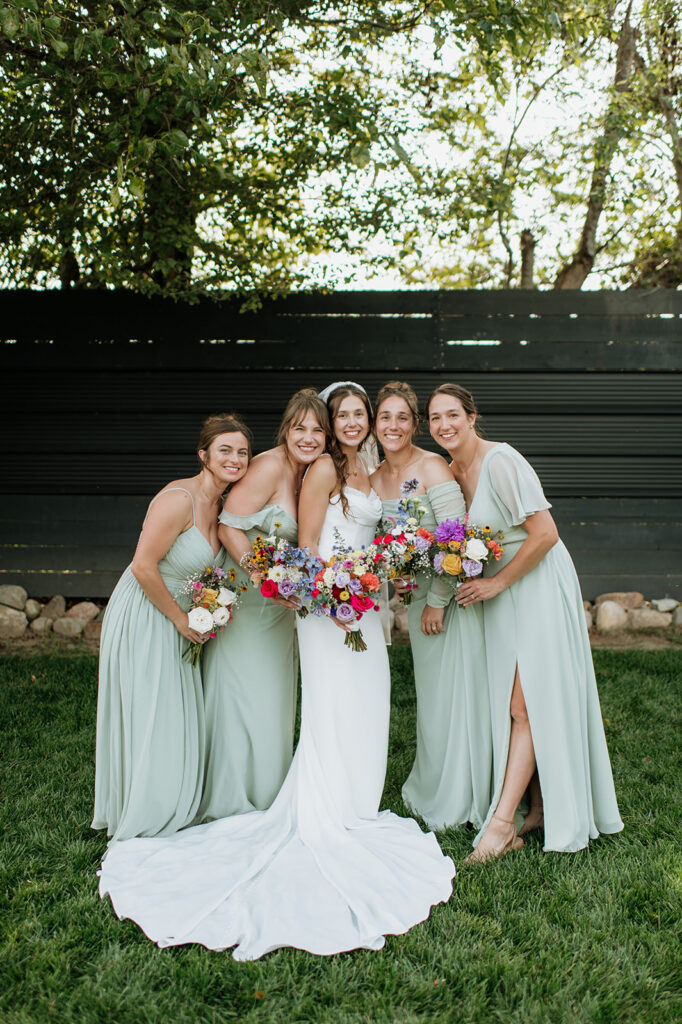 Bride and bridesmaids posing outdoors during a summer Empeiria 110 wedding in Rochester, Indiana