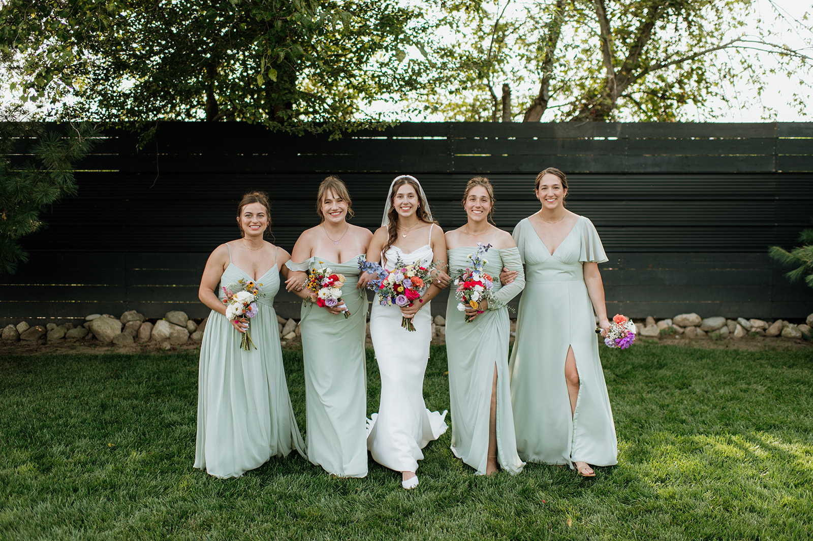 Bride and bridesmaids posing outdoors during a summer Empeiria 110 wedding in Rochester, Indiana