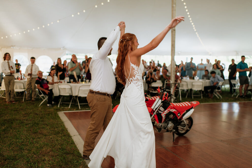 Bride and groom riding into their backyard wedding reception on their dirt bikes