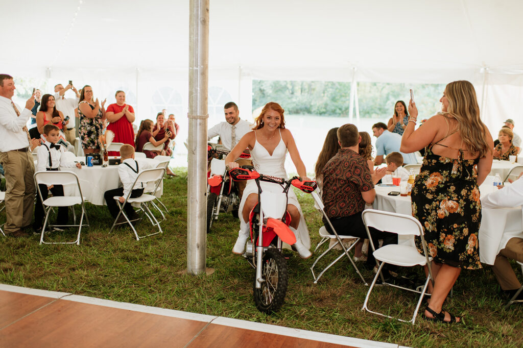 Bride and groom riding into their backyard wedding reception on their dirt bikes