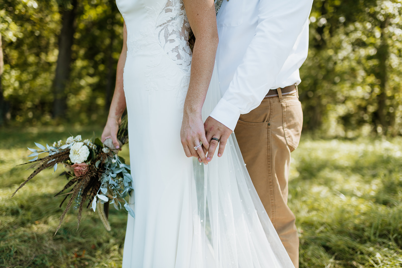 Close up shot of a bride and groom holding hands during their fall wedding photos