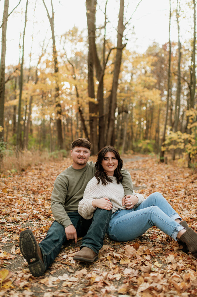 Couple sitting together for their outdoor fall engagement shoot