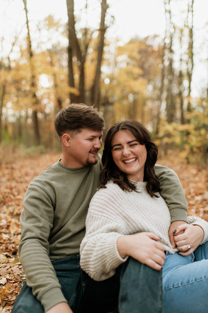 Couple sitting together for their outdoor fall engagement shoot