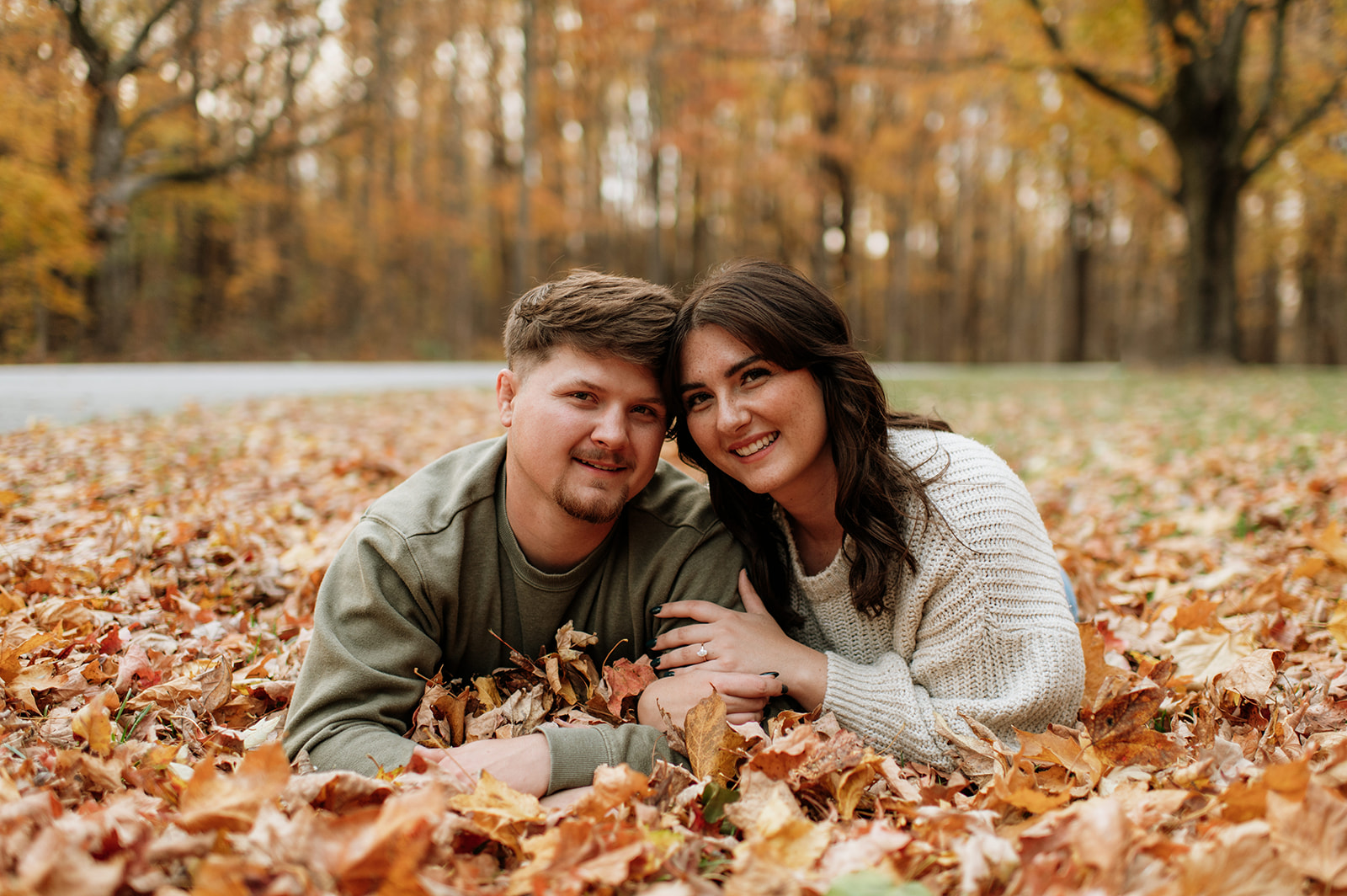 Man and woman posing in the leaves during their fall outdoor engagement shoot