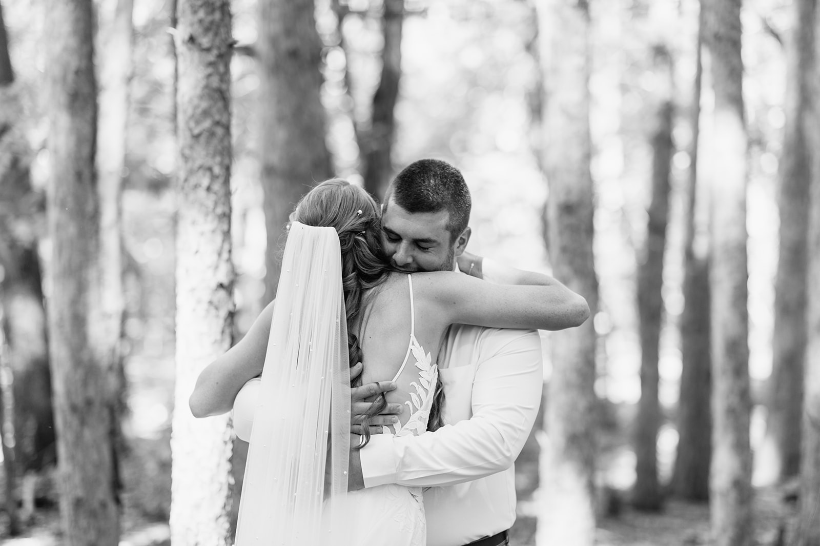 Black and white photo of a bride and groom hugging during their first look