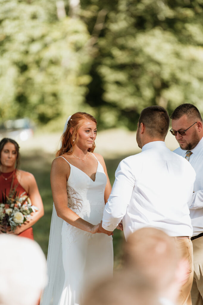 Bride and groom holding hands during their fall backyard wedding ceremony