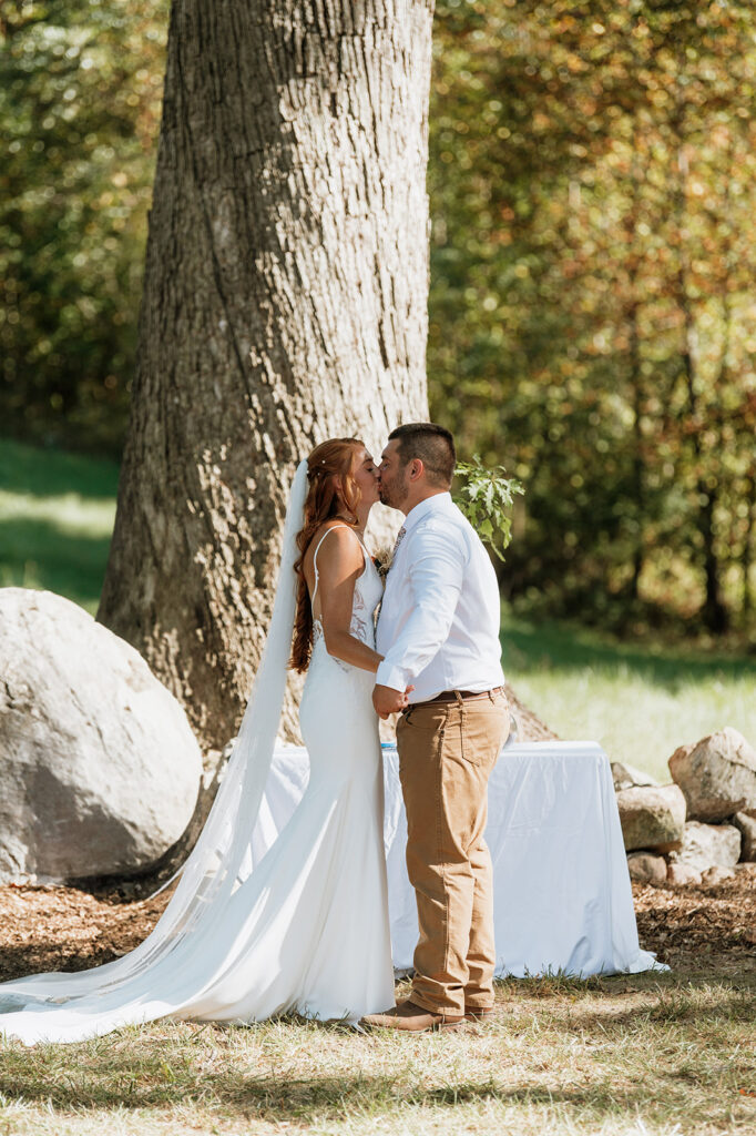 Bride and groom kissing during their fall backyard wedding ceremony