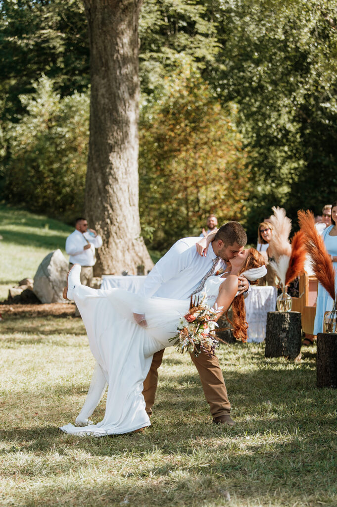 Bride and groom doing a dup kiss at the end of the aisle after their fall backyard wedding ceremony