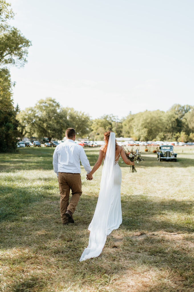 Bride and groom walking to their vintage car after their fall backyard wedding ceremony