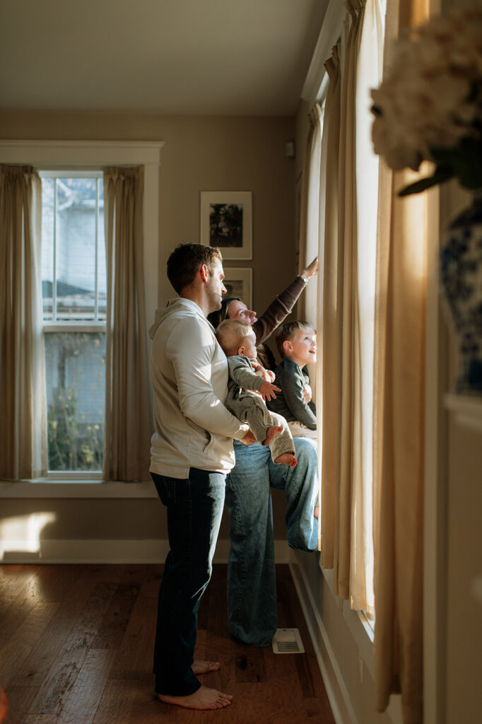 Family of four looking out their window during their at-home Northern Indiana family photos