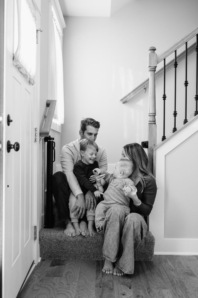 Black and white photo of a family of four sitting on their steps at home