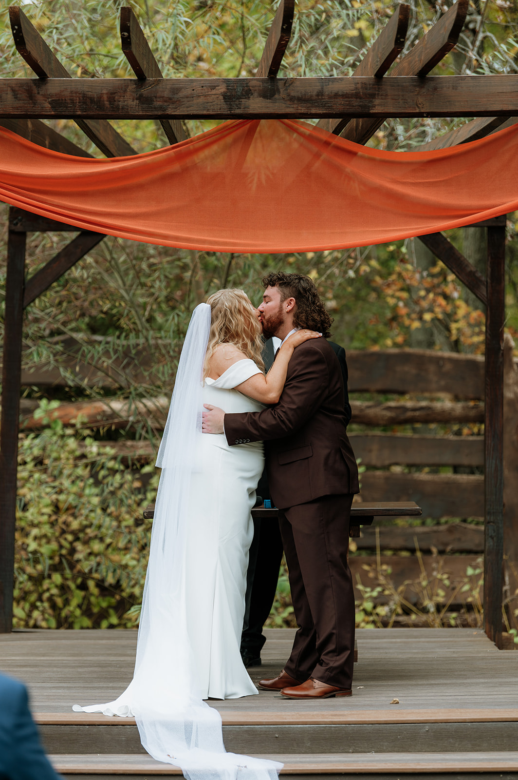 Bride and groom kissing during their outdoor fall Willow Acres wedding ceremony on the Pergola