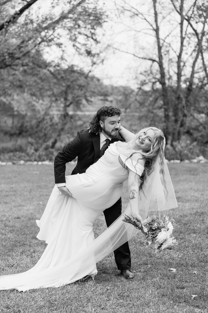 Black and white photo of a bride and groom posing during their outdoor fall Willow Acres wedding ceremony on the Pergola