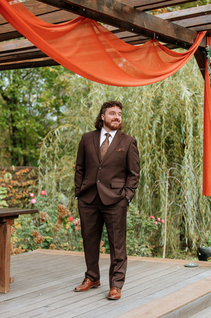 Groom watching his bride walk down the aisle during their outdoor fall Willow Acres wedding ceremony on the Pergola