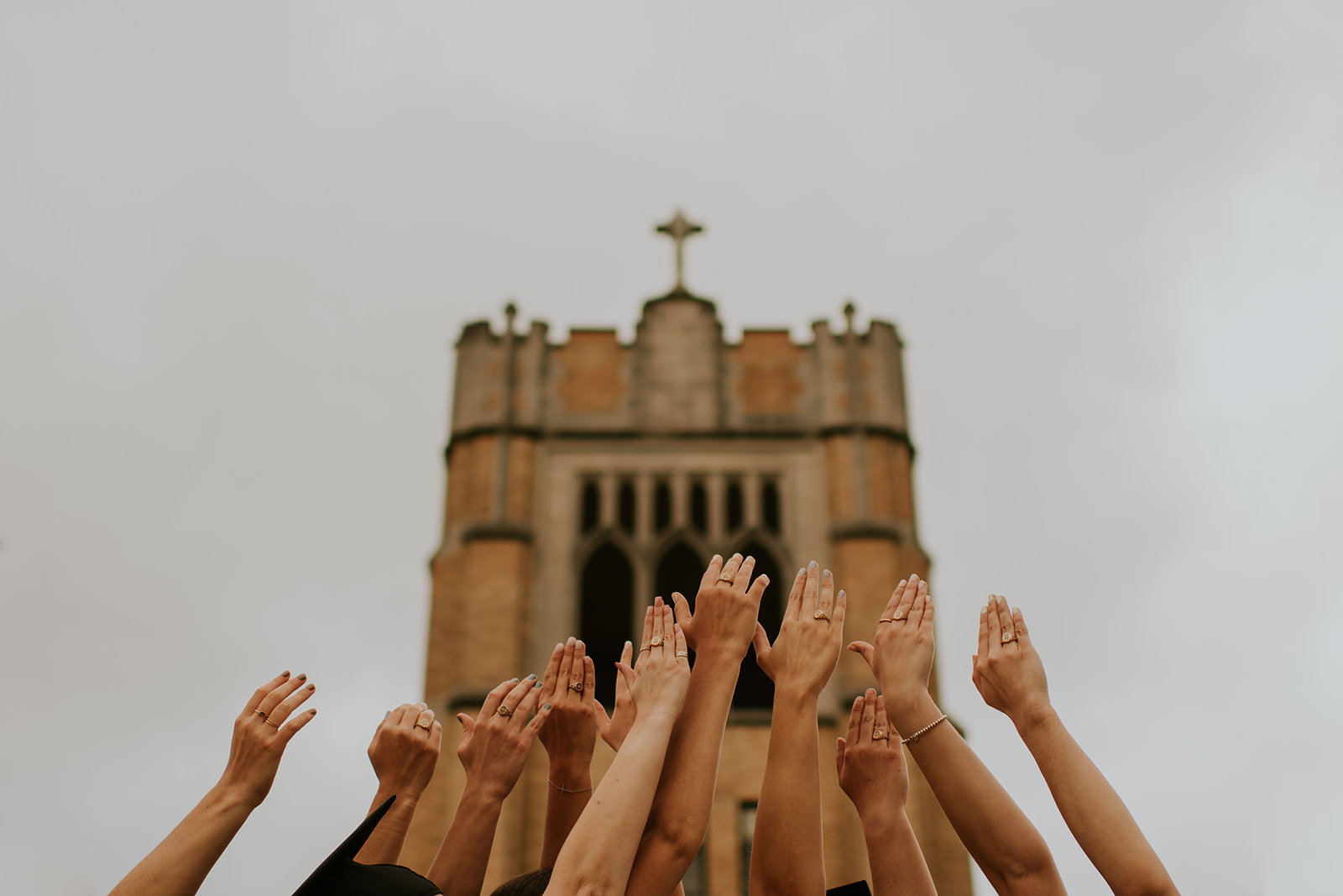 Group holding their hands up to the sky showing off their class rings