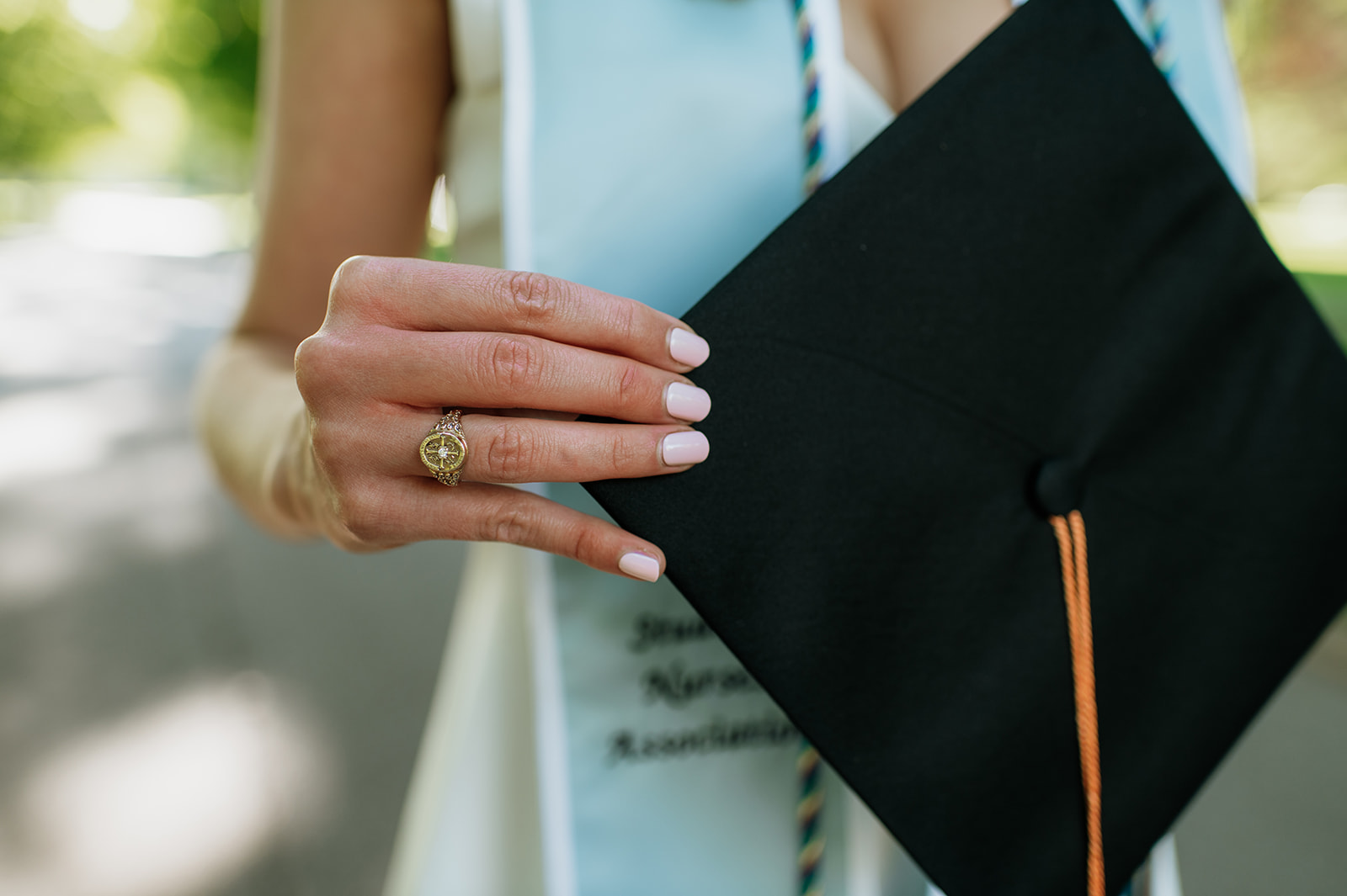 Close up shot of a grad wearing her class ring and holdingher cap