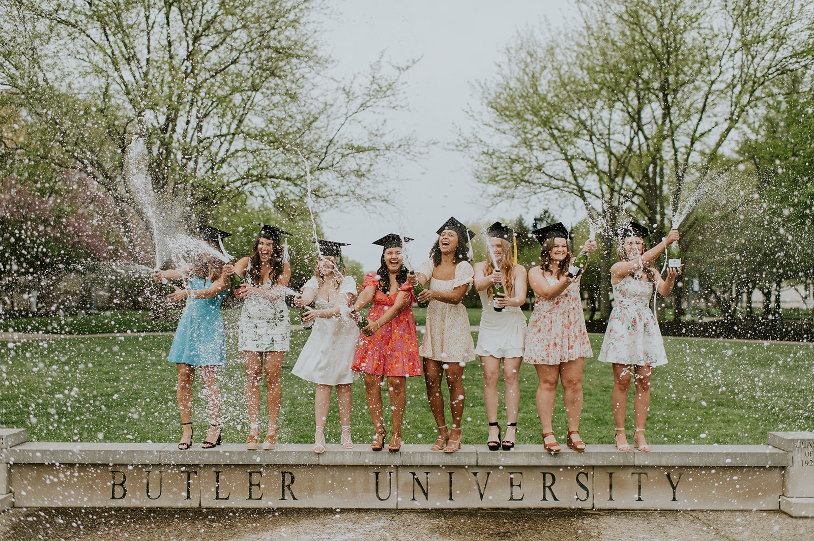 Women popping bottles of champagne for their Northern Indiana gradation photos