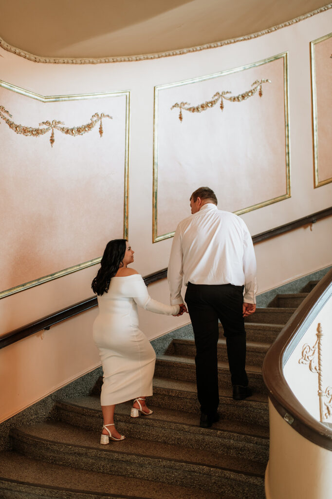 Couple holding hands and walking up the stairs at The Morris Performing Arts Center
