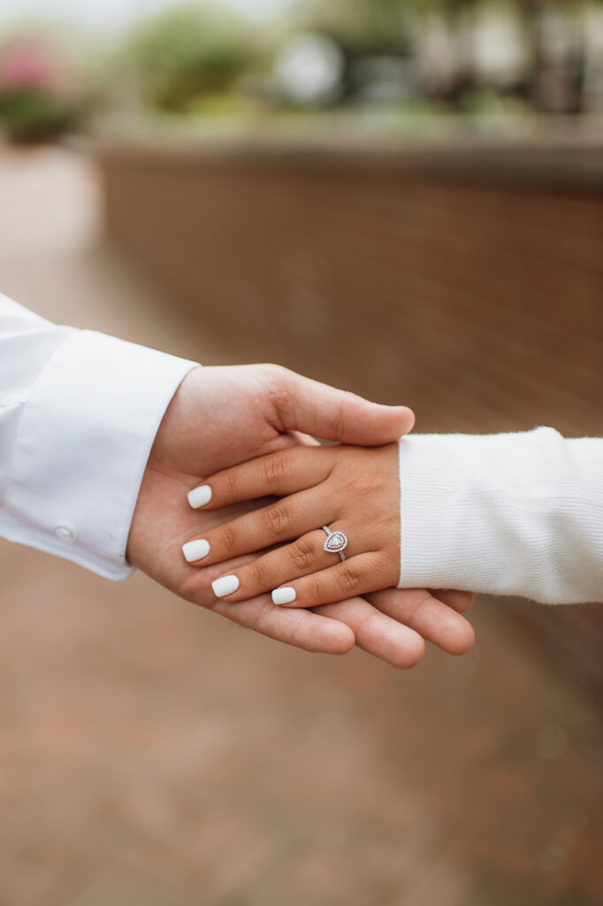 Couple holding hands and showing off an engagement ring