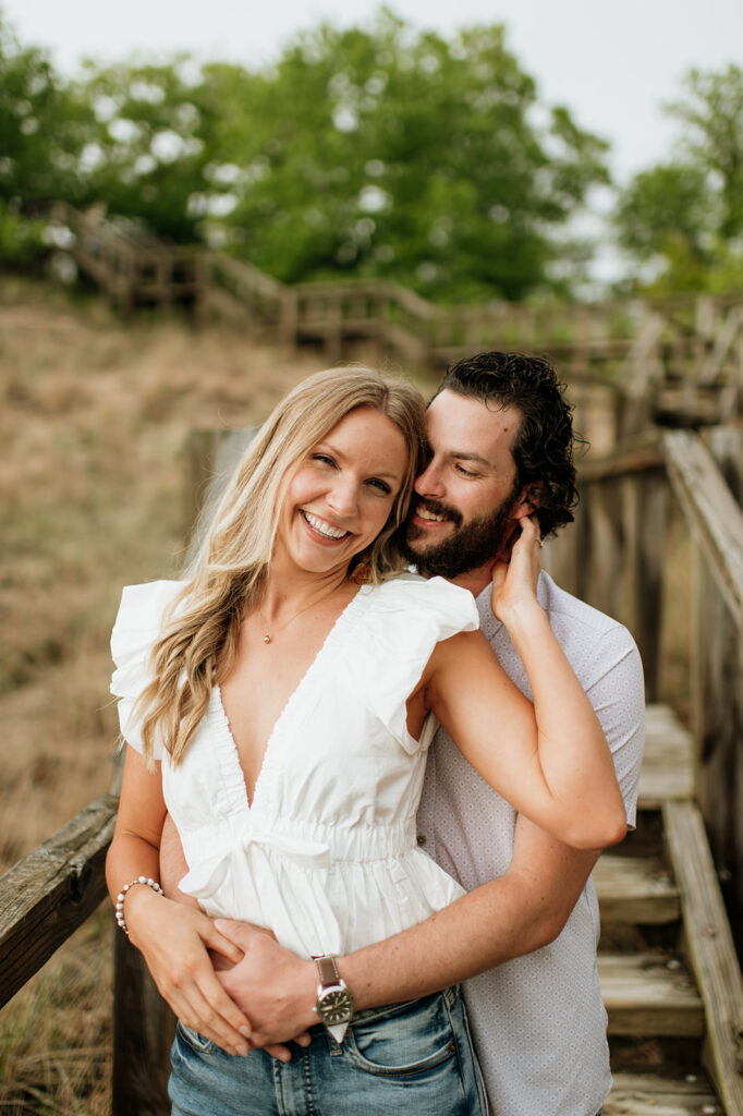 Couple posing on a boardwalk staircase for their Indiana Dunes National Park engagement photos