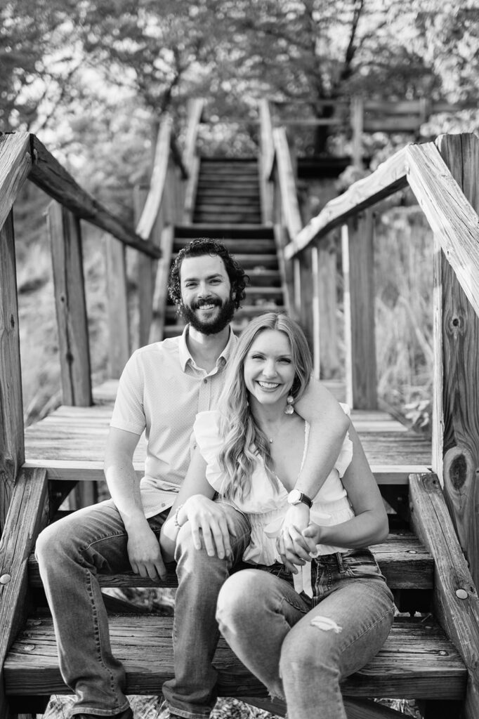 Black and white engagement photo of a couple sitting on outdoor stairs during their engagement shoot