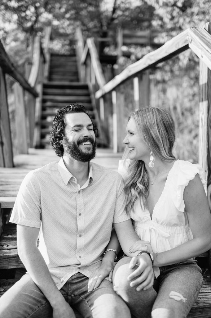 Black and white engagement photo of a couple sitting on outdoor stairs during their engagement shoot