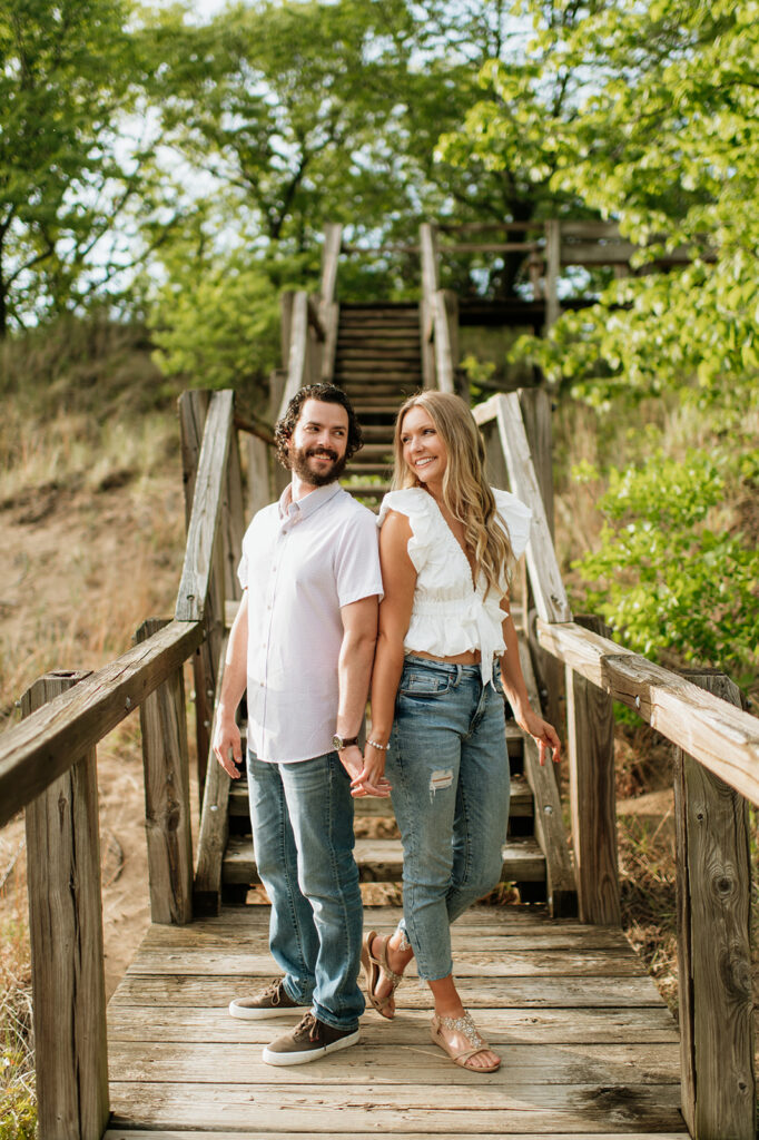 Couple posing on a boardwalk staircase for their Indiana Dunes National Park engagement photos