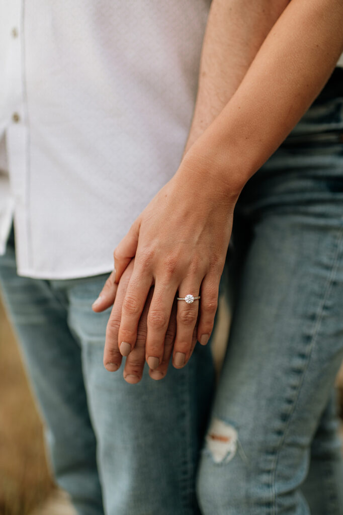 Couple holding hands and showing off an engagement ring